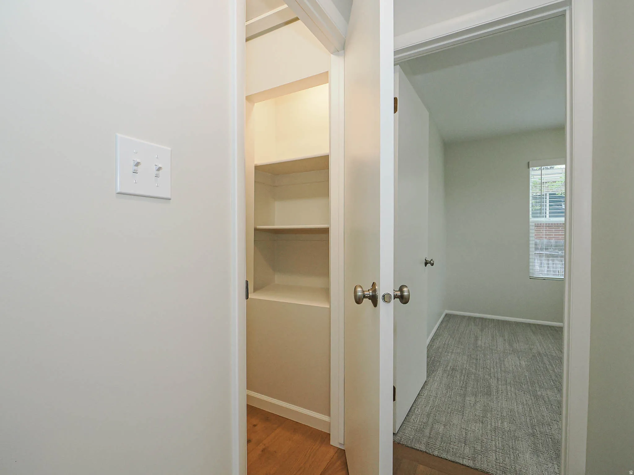 Hallway with light wood-finish flooring, white walls, and a built-in shelving unit