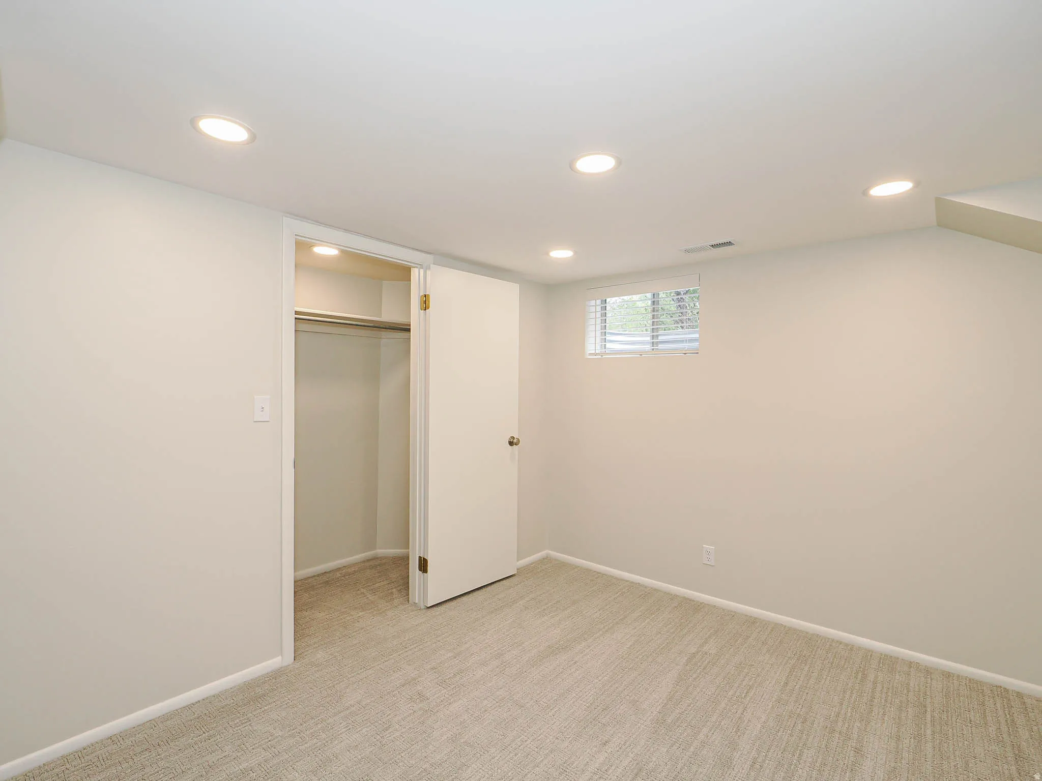 Carpeted room featuring recessed lighting, a window with blinds, a built-in closet with hanging rod, and light-toned walls