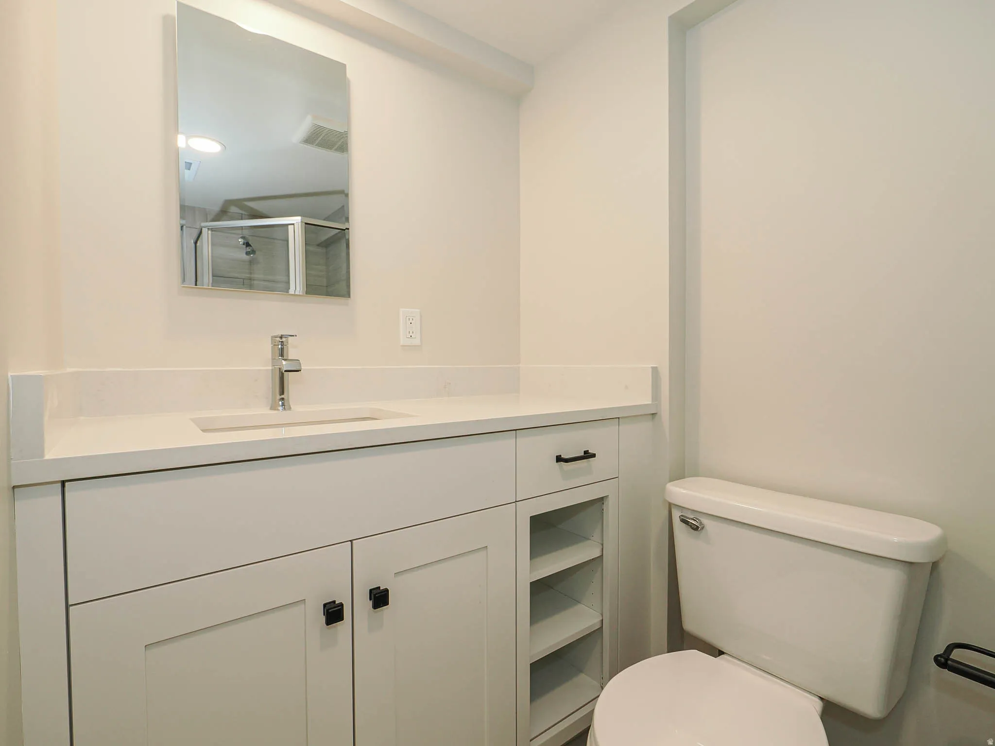 Vanity with light-colored countertop, integrated rectangular sink, and chrome-finish faucet
