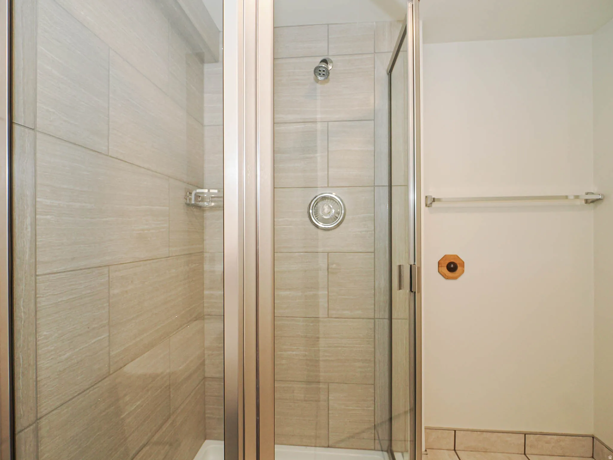 Shower enclosure with glass paneling and a chrome shower head