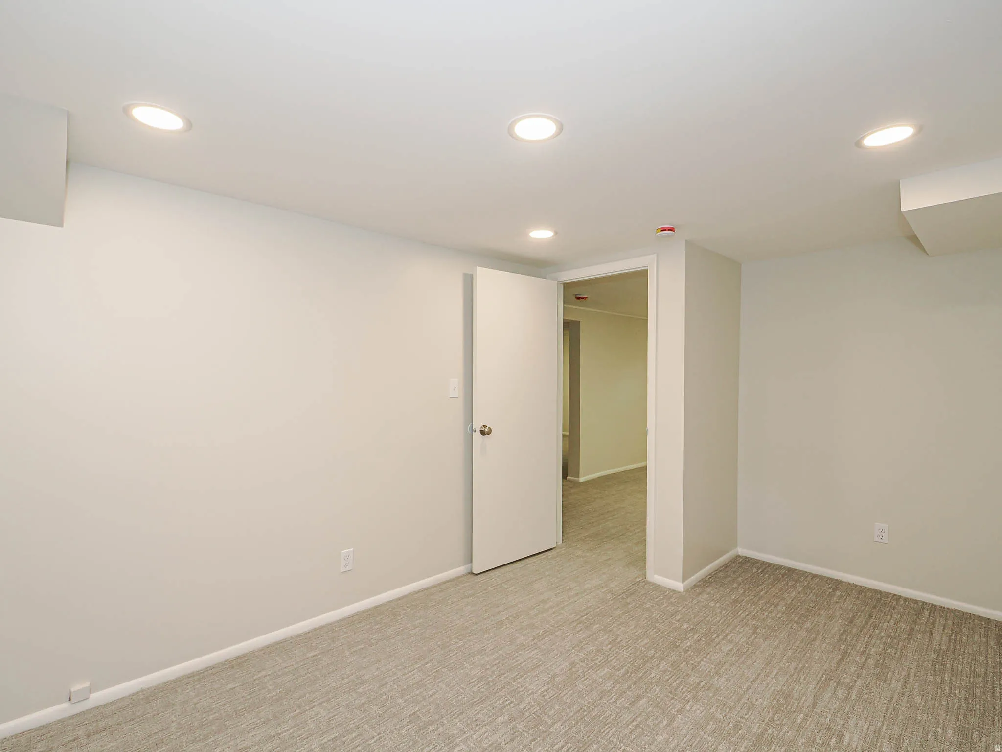 Carpeted room featuring a neutral wall color, white baseboards, a white door, and recessed ceiling lighting