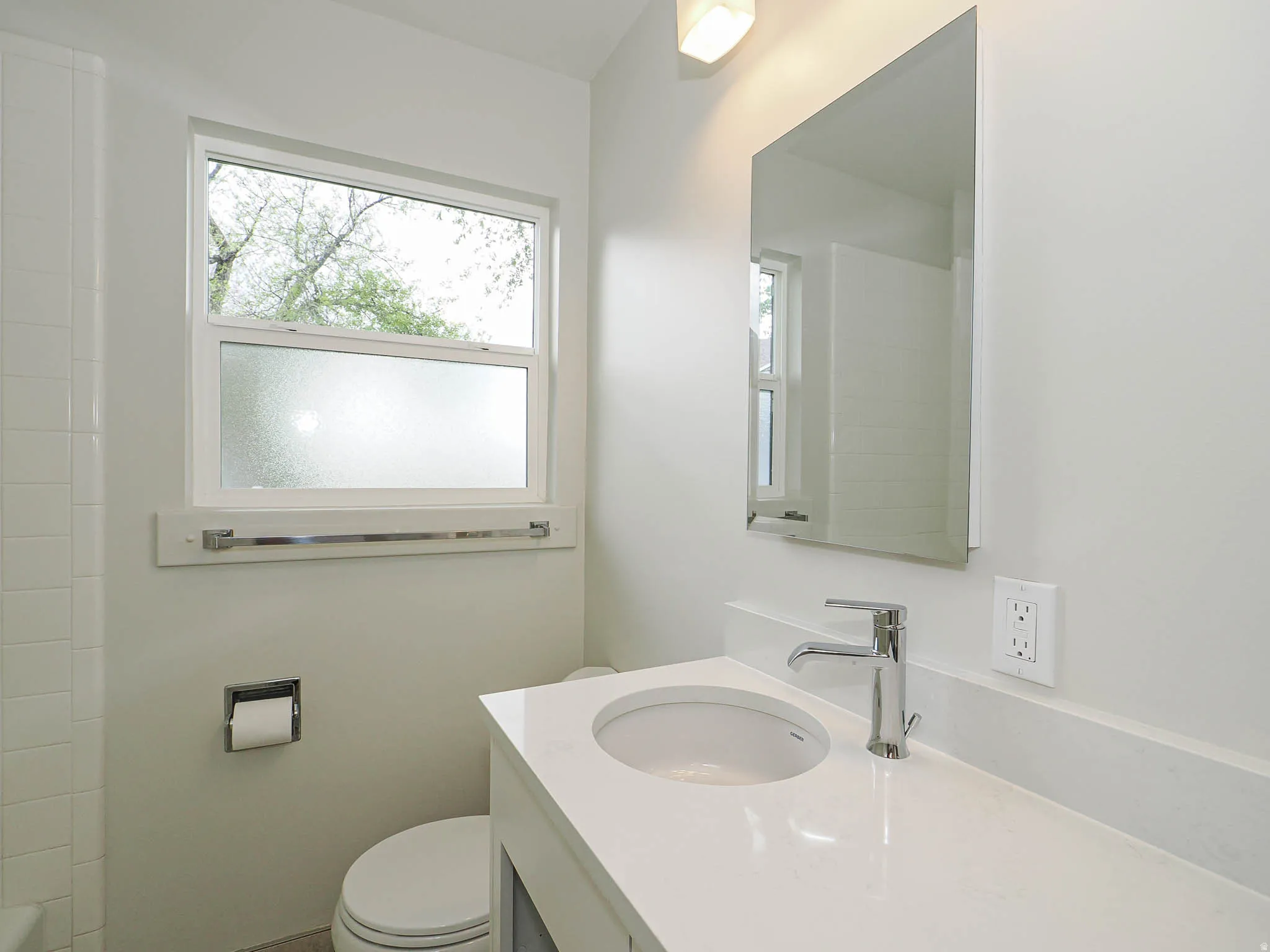 Bathroom featuring a single white vanity with an integrated sink, a polished chrome faucet, a rectangular mirror, and a white-framed window