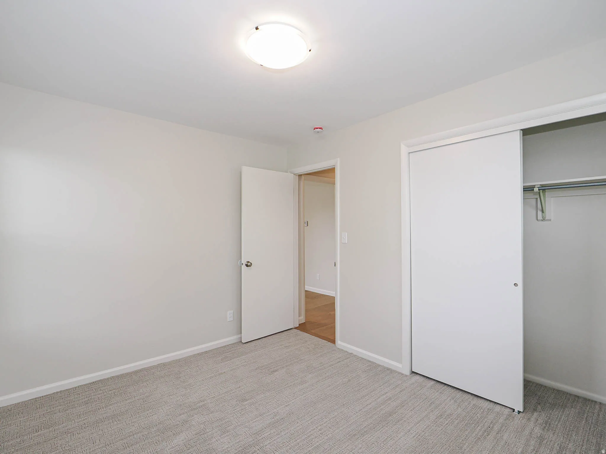 Interior room featuring light gray carpet flooring, white painted walls, and white baseboards