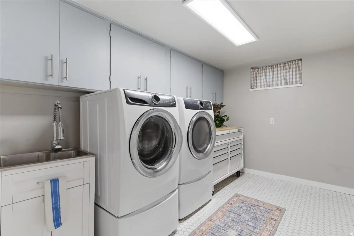 Dedicated utility space featuring extensive overhead cabinetry, a dual-basin stainless steel sink with a gooseneck faucet, and hexagonal floor tiling