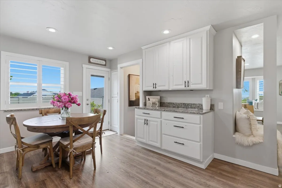 Bright dining area with wood-finish flooring, recessed lighting, and a window with plantation shutters