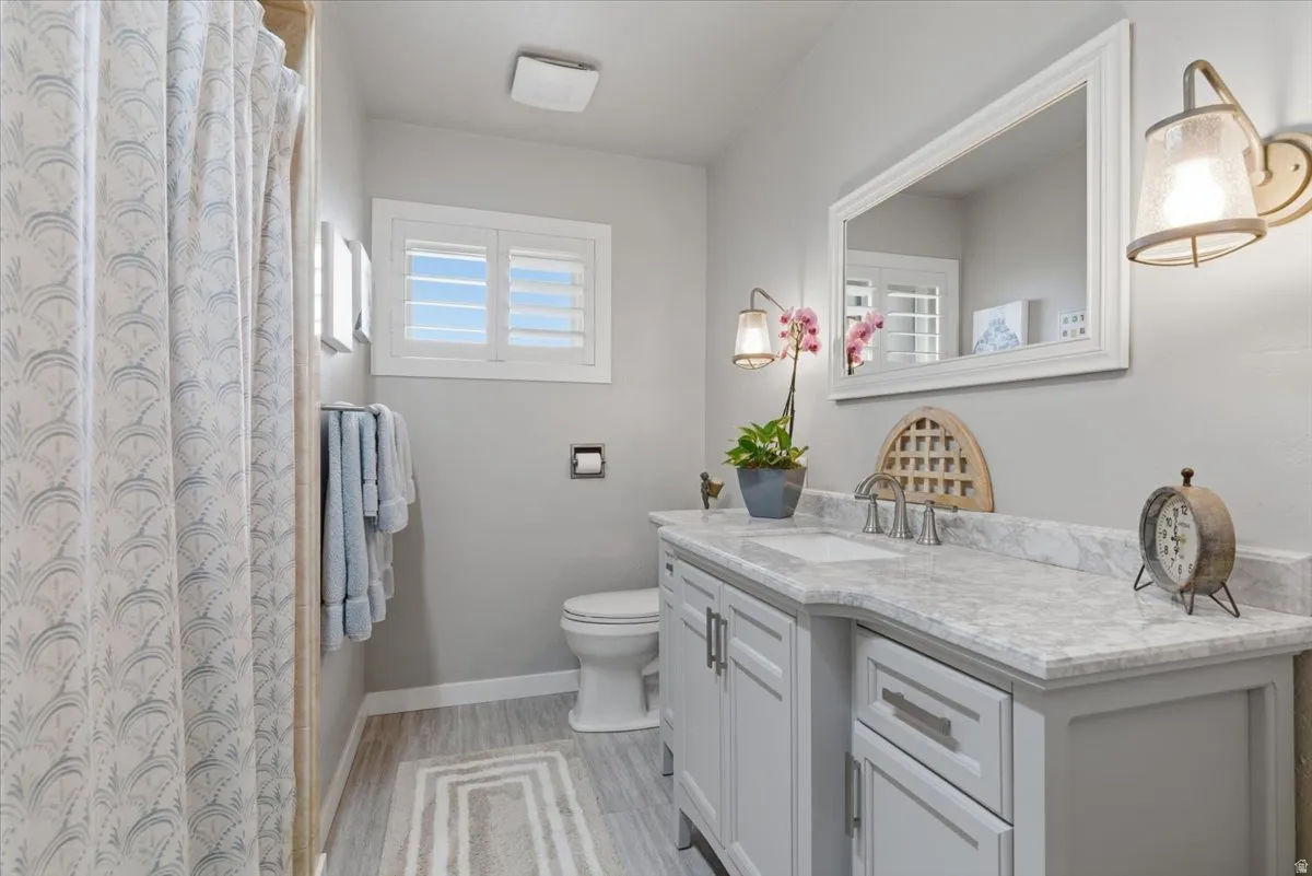 Bathroom featuring a vanity with light-toned countertops and dual sinks, complemented by light gray cabinetry with brushed nickel hardware