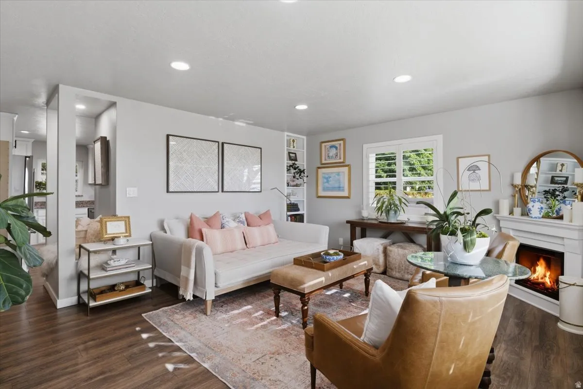 Living area featuring wood-finish flooring, recessed lighting, and a white fireplace with a mantel