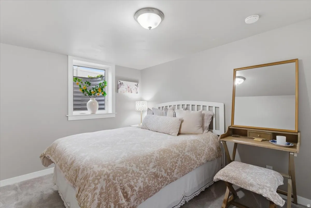 Bedroom featuring light gray walls, plush gray carpeting, a white bed frame, and a window with a white frame