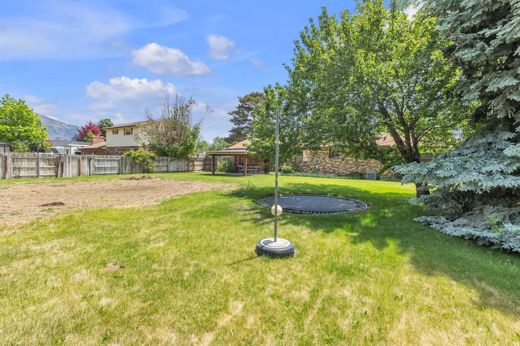 Expansive backyard featuring a combination of manicured lawn and a cleared, level section