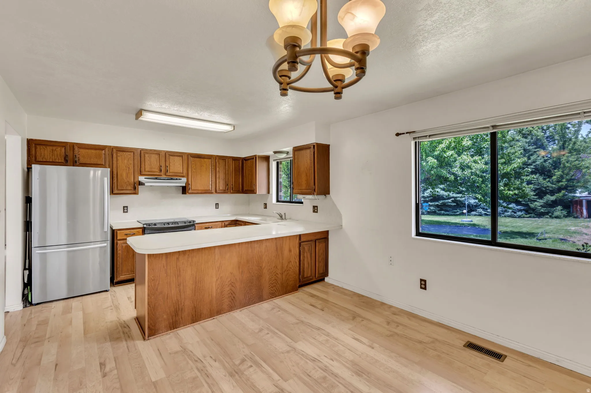 Kitchen featuring wood cabinetry, light-toned countertops, and wood-finish flooring