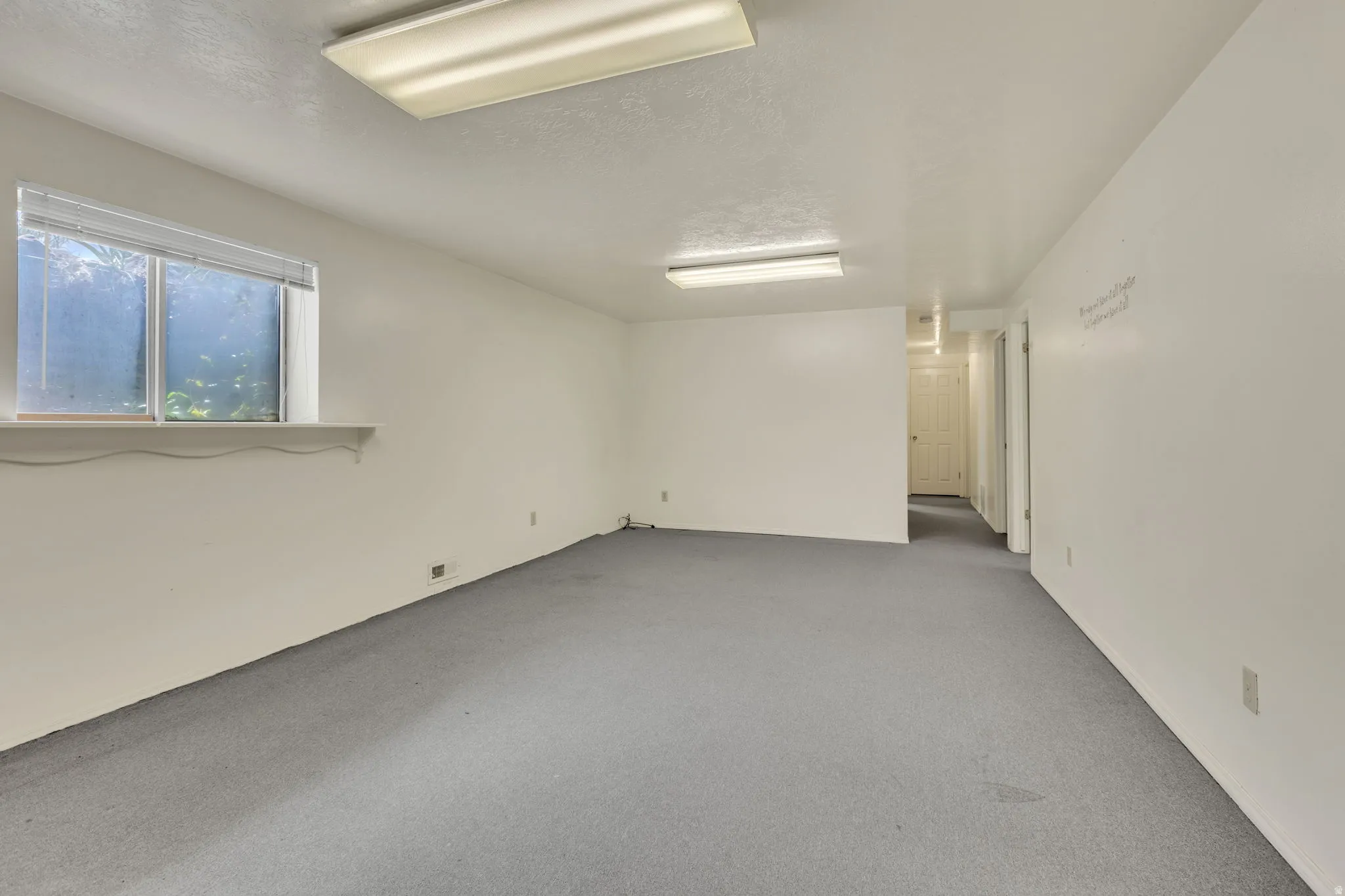 Spacious room featuring neutral carpeting and white wall finishes