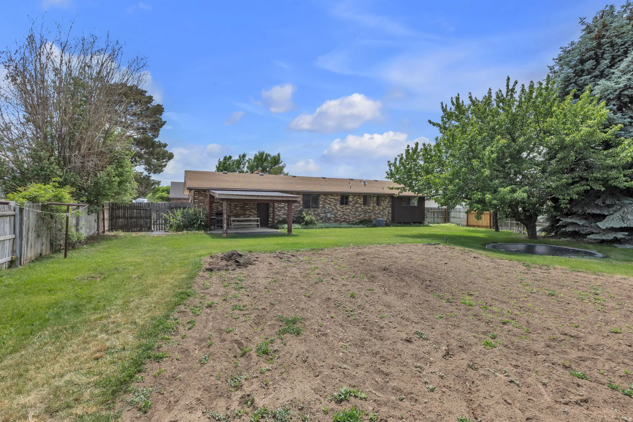 Expansive backyard featuring a covered patio, a rock-clad exterior, and mature trees Garden spot