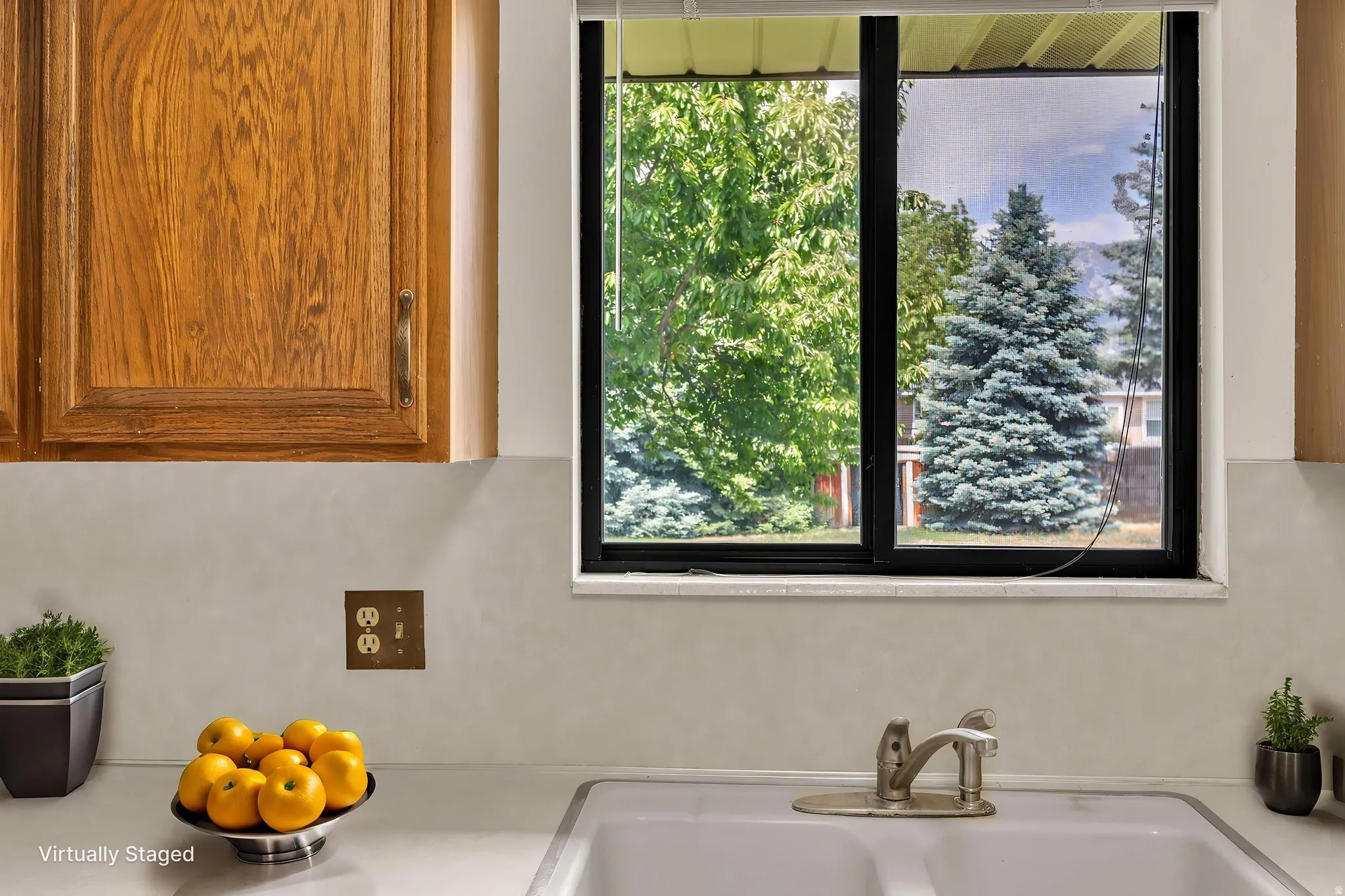 Virtually Staged -Kitchen sink area featuring a dual-basin sink with a single-handle faucet, set into a light-toned countertop