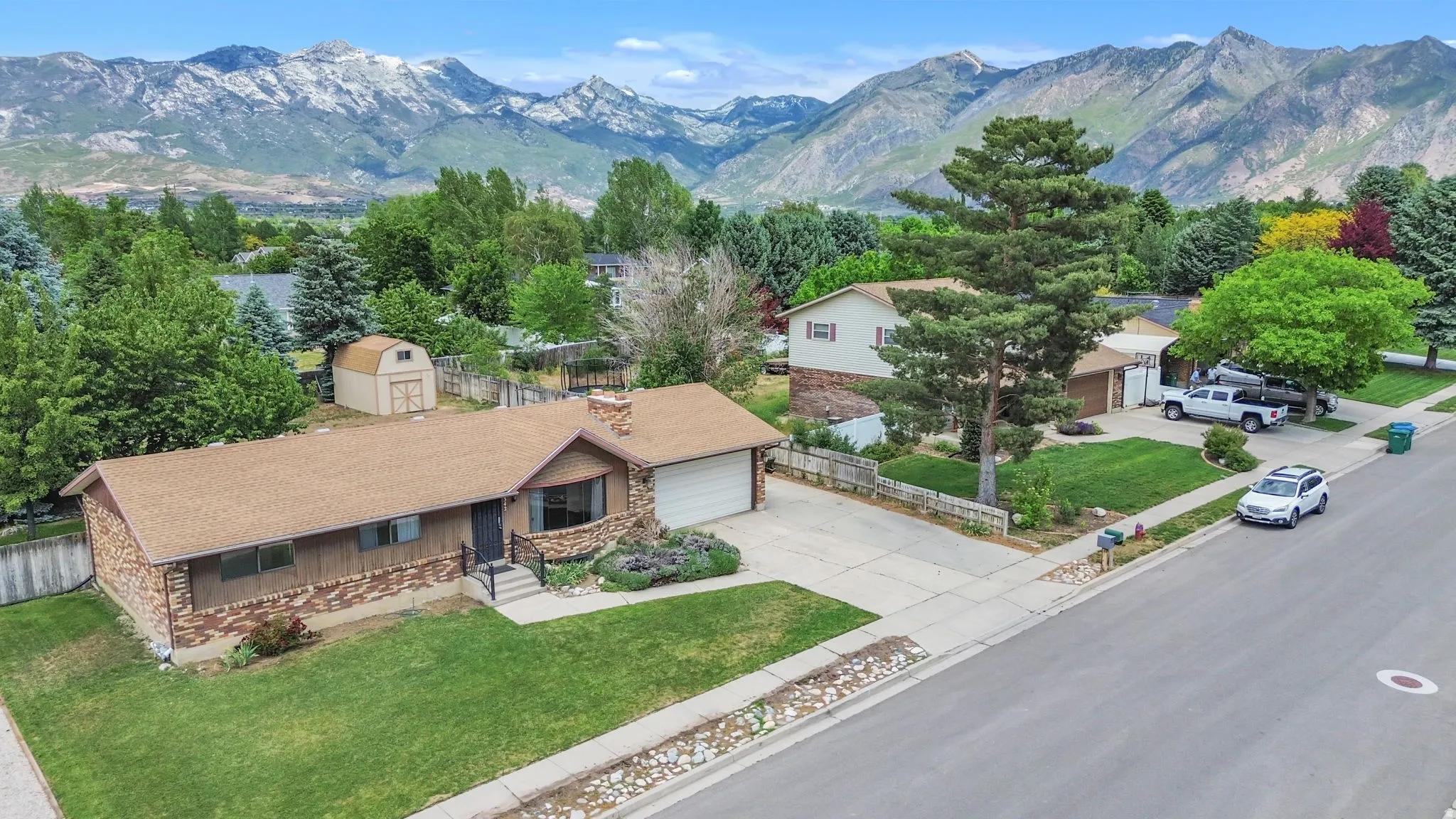 Ranch-style home featuring a brick and wood-panel exterior, an attached garage, and a front lawn with mature landscaping