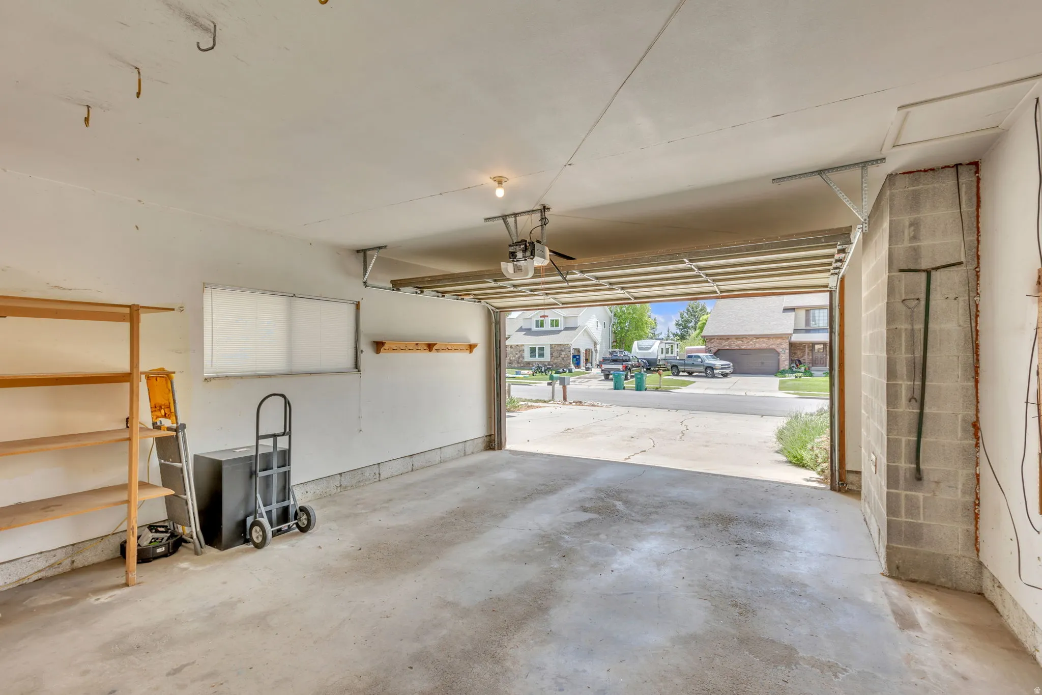 Attached two-car garage featuring a concrete floor, built-in shelving, and a window for natural light