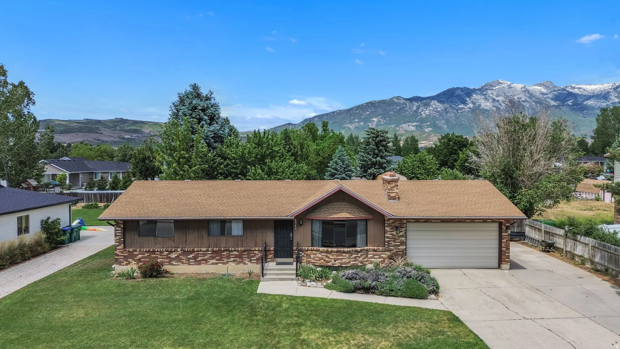 Ranch-style residence featuring a brick and wood siding facade, attached two-car garage, and manicured front lawn