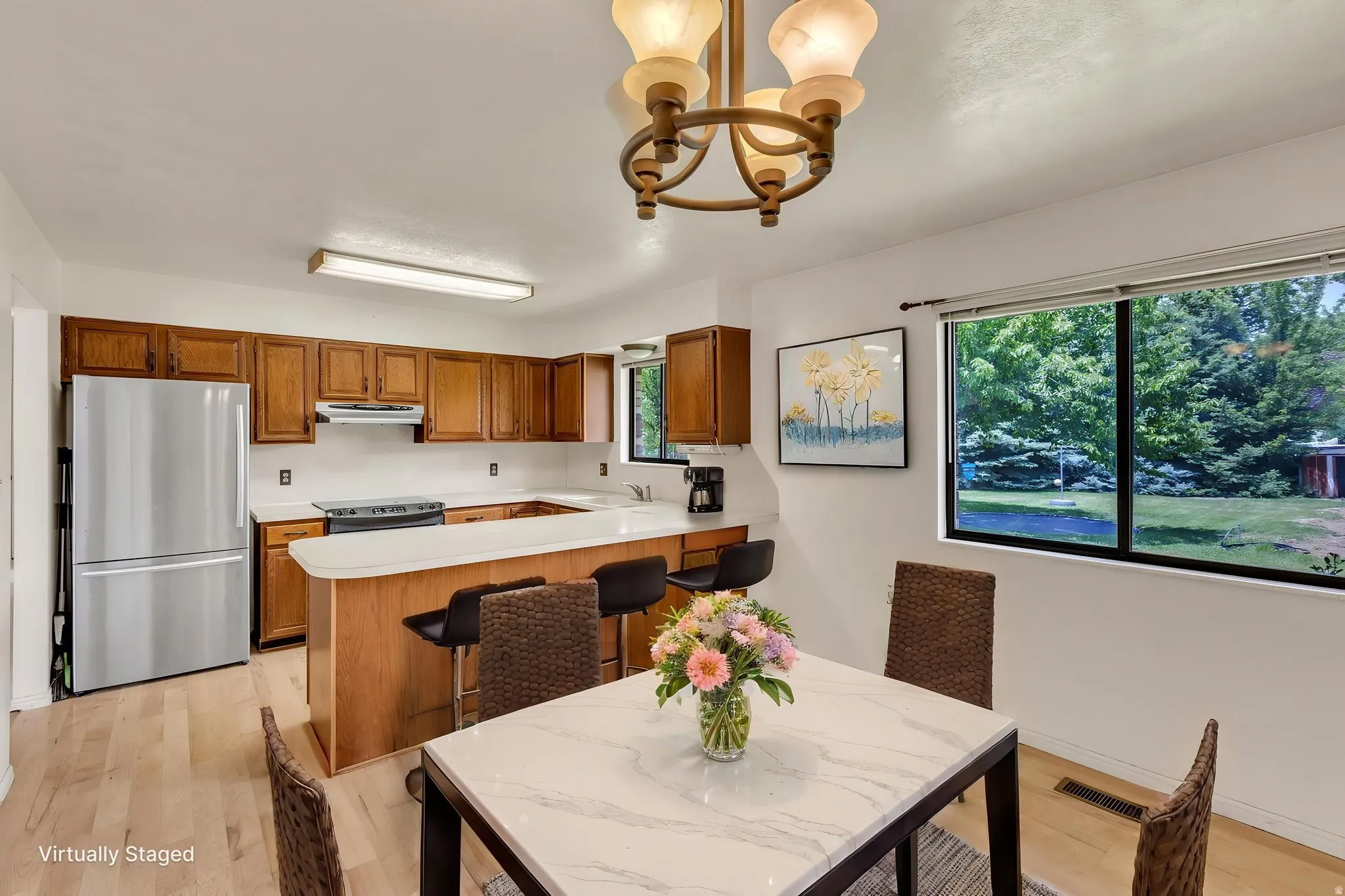 Virtually Staged -Kitchen and dining area featuring wood-finish flooring, white countertops, and a kitchen island with seating