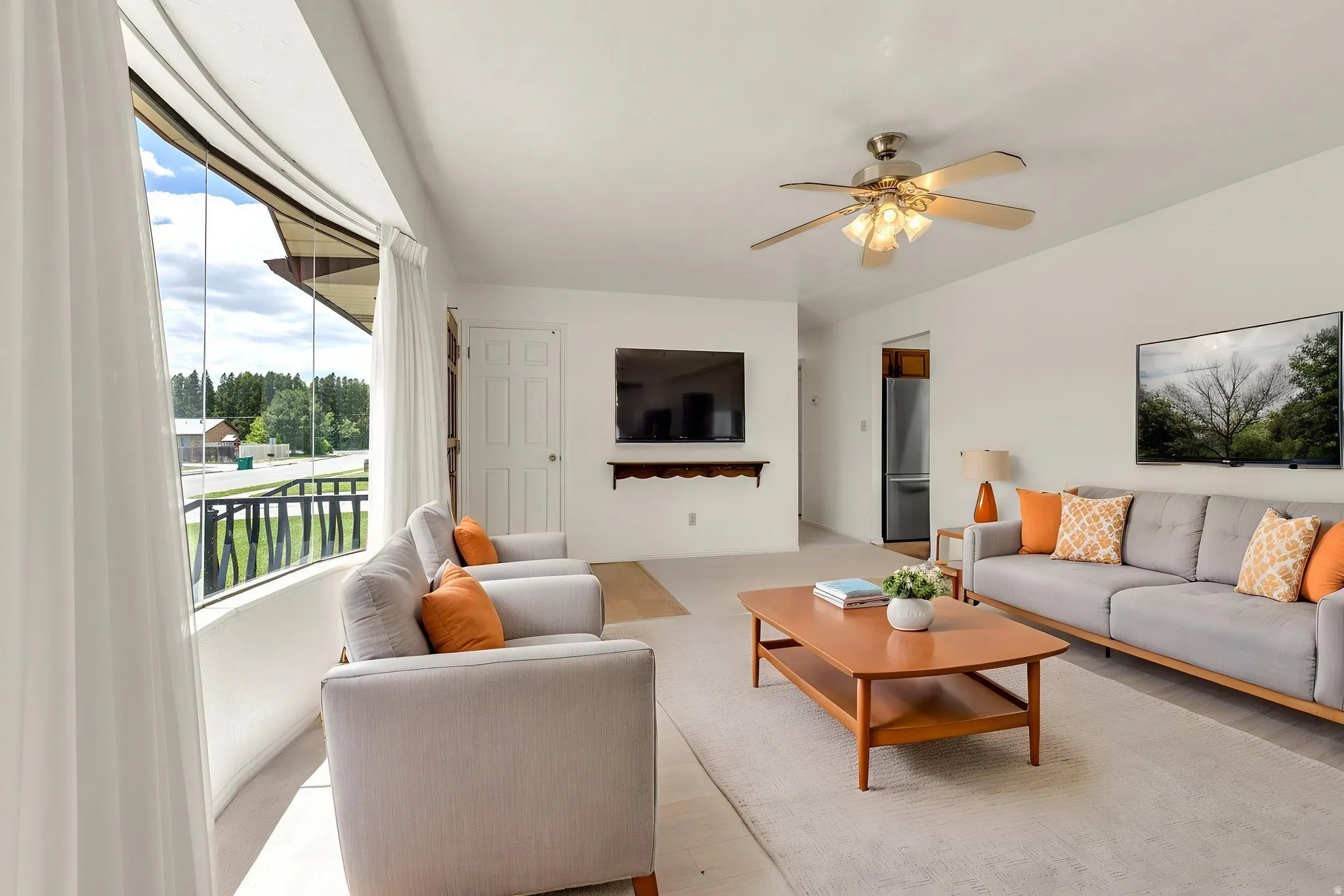 Spacious interior with an expansive curved window line, light wood-finish flooring, and a ceiling fan with integrated lighting