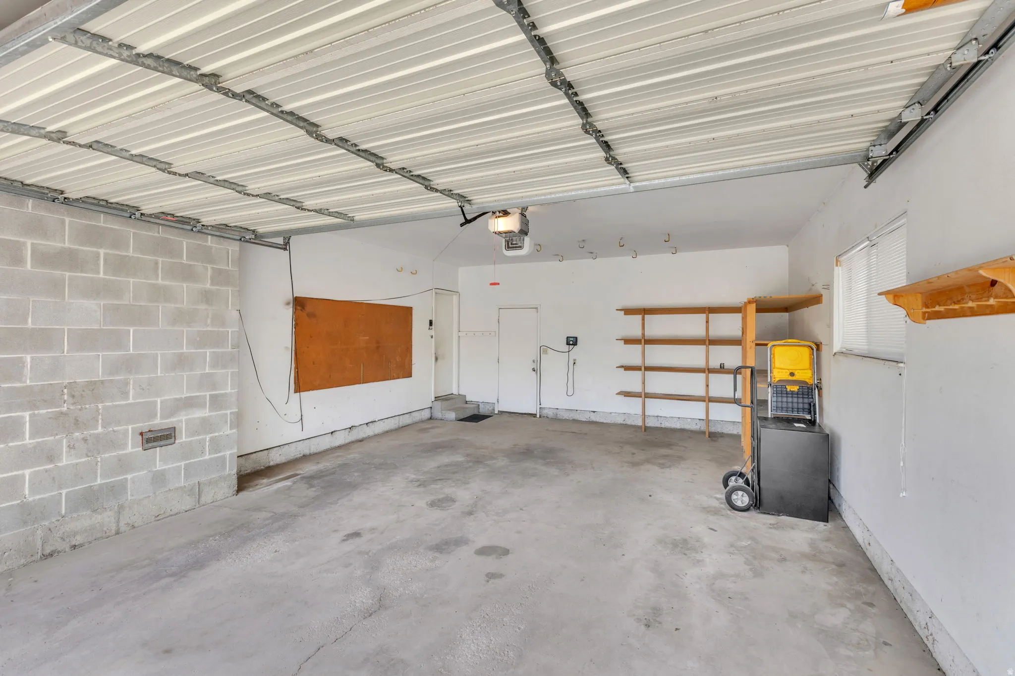 Spacious garage featuring a concrete floor, exposed block wall, and white painted walls