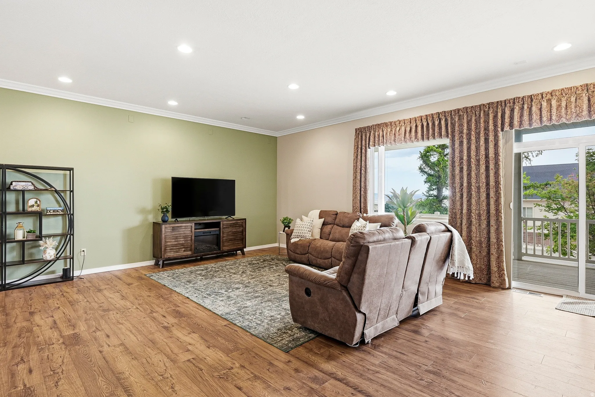 Spacious living area featuring wood-finish flooring, recessed lighting, and crown molding