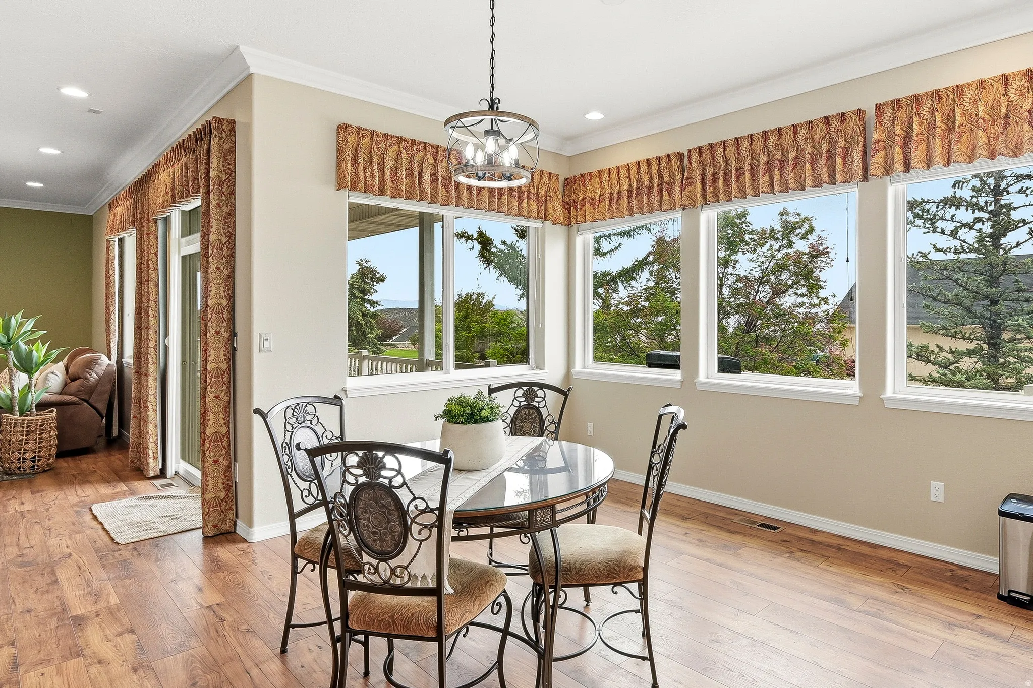 Bright dining area with wood-finish flooring, featuring a large window array