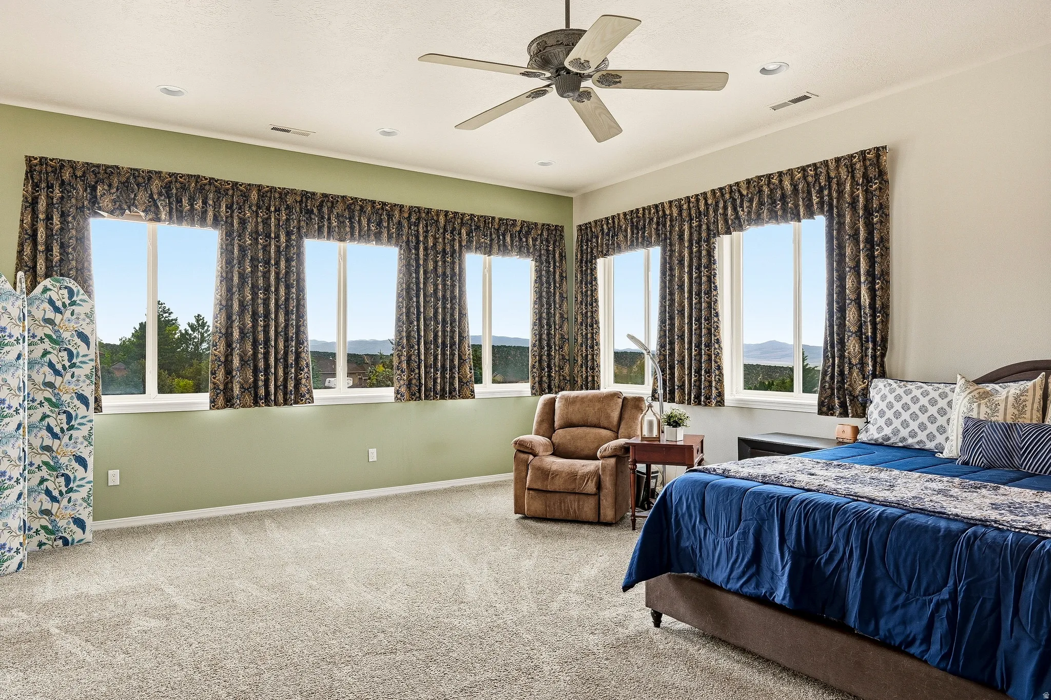 Spacious interior room featuring multiple large windows, wall-to-wall carpeting, recessed lighting, and a ceiling fan
