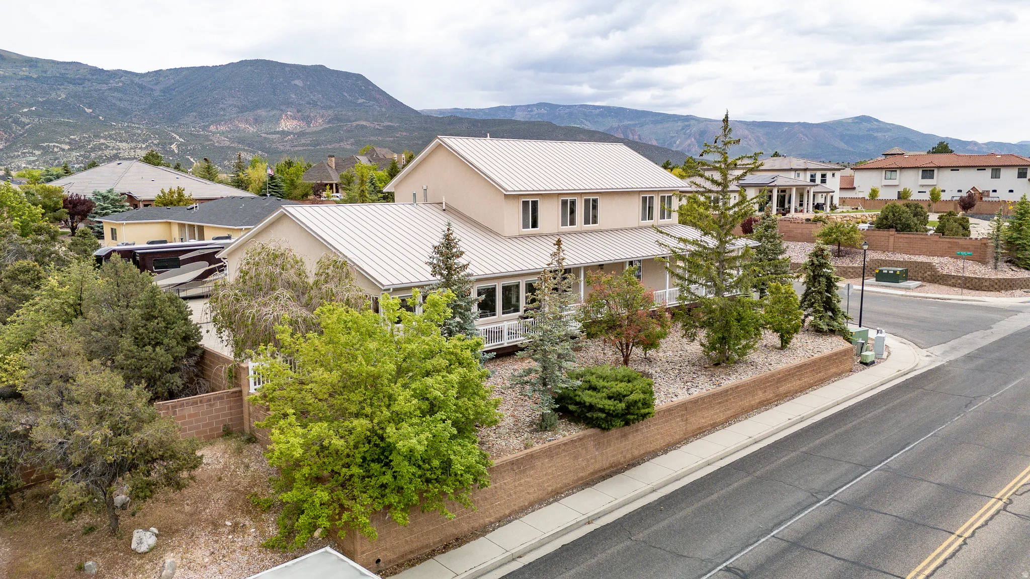 Two-story stucco residence with a metal roof, situated on a terraced lot