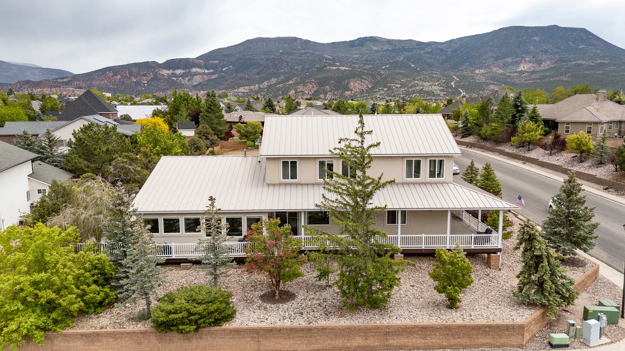 Two-story residence featuring a neutral exterior, a standing seam metal roof, and an expansive covered porch with white railings
