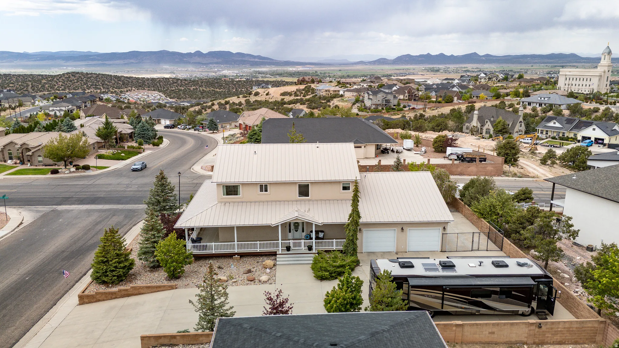 Two-story residence featuring a covered front porch, a two-car garage, and a side yard with a fenced perimeter
