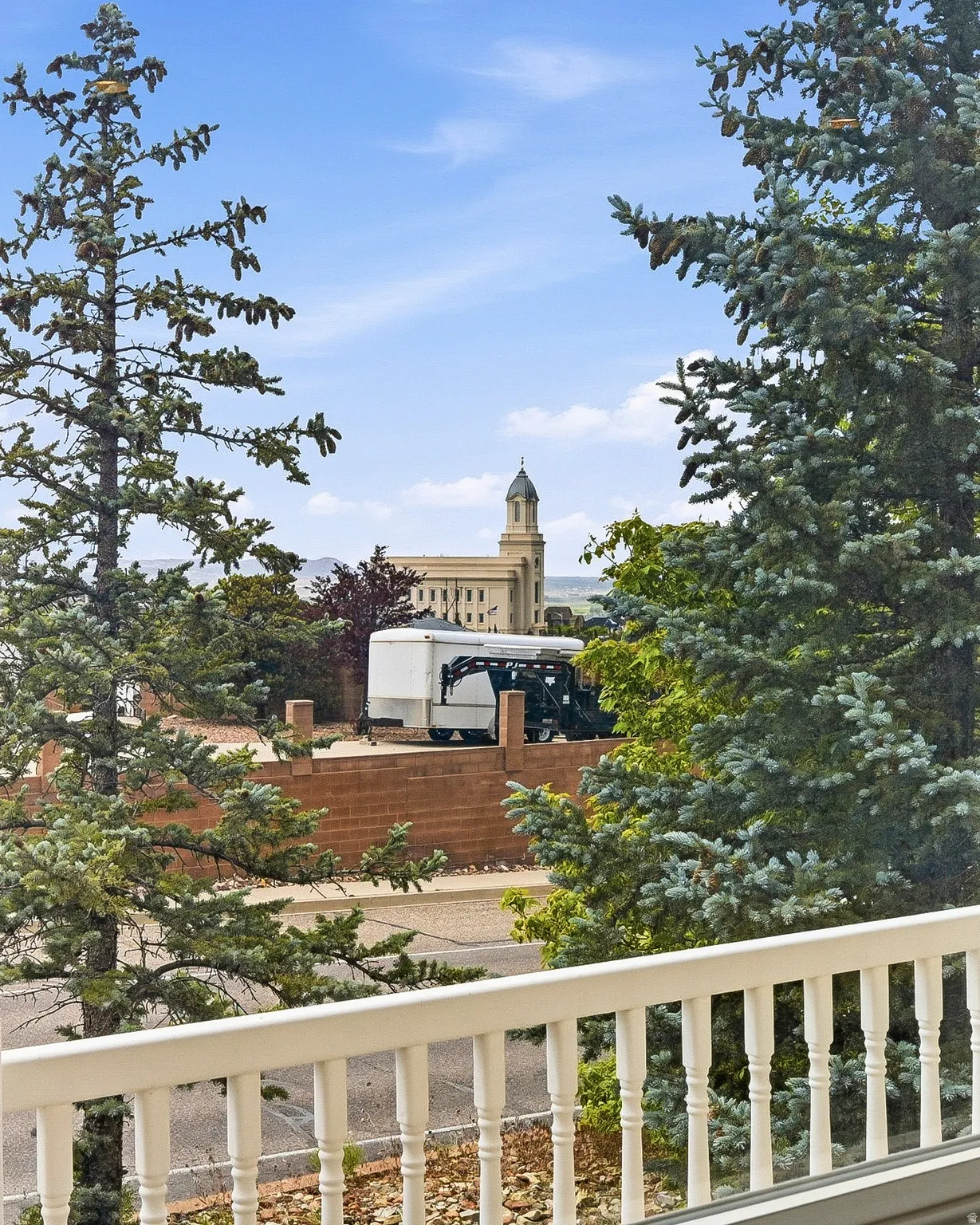 Balcony with a white balustrade overlooking a prominent building with a domed tower