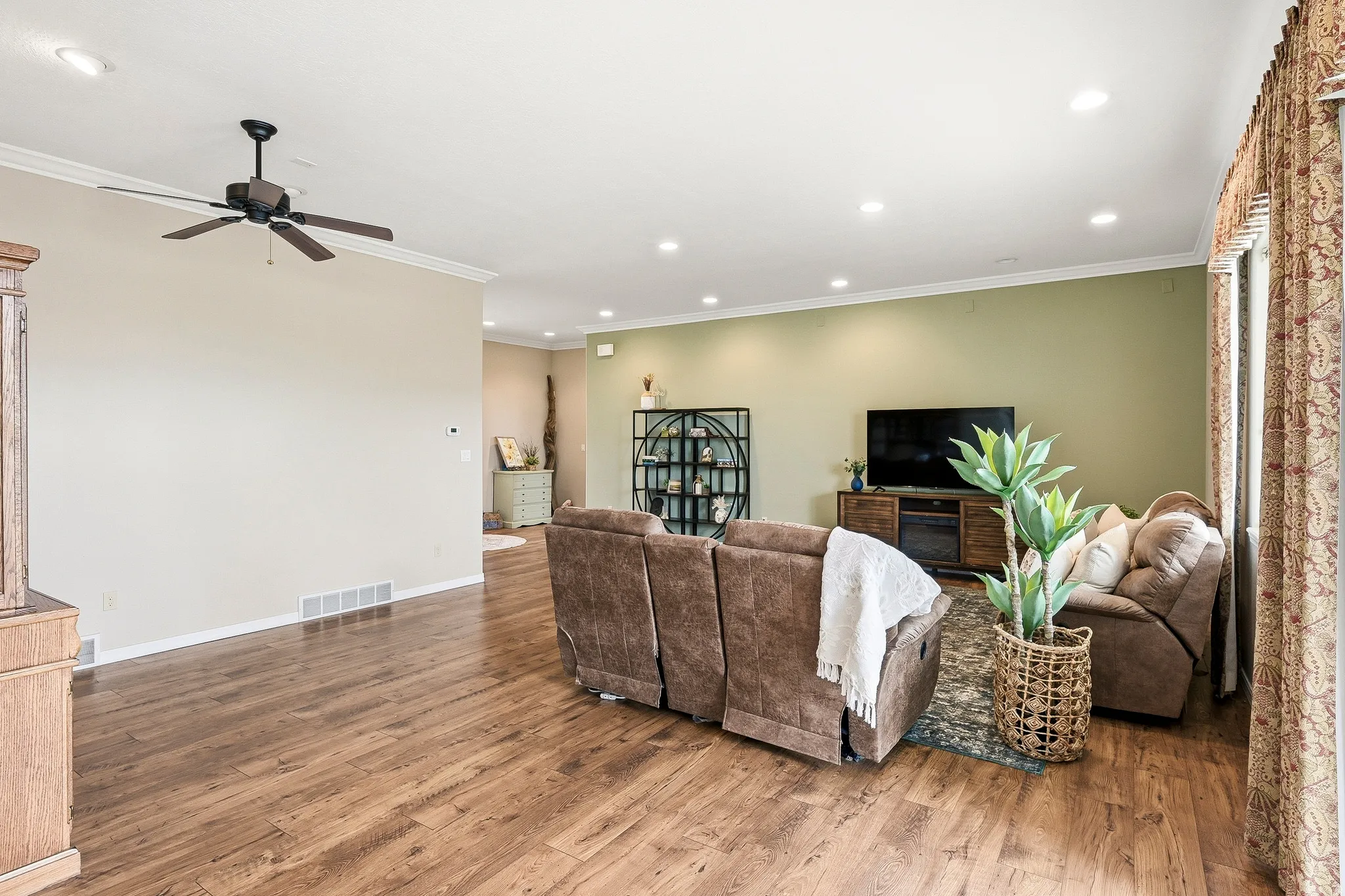 Spacious living area featuring wood-finish flooring, recessed lighting, crown molding, and a ceiling fan