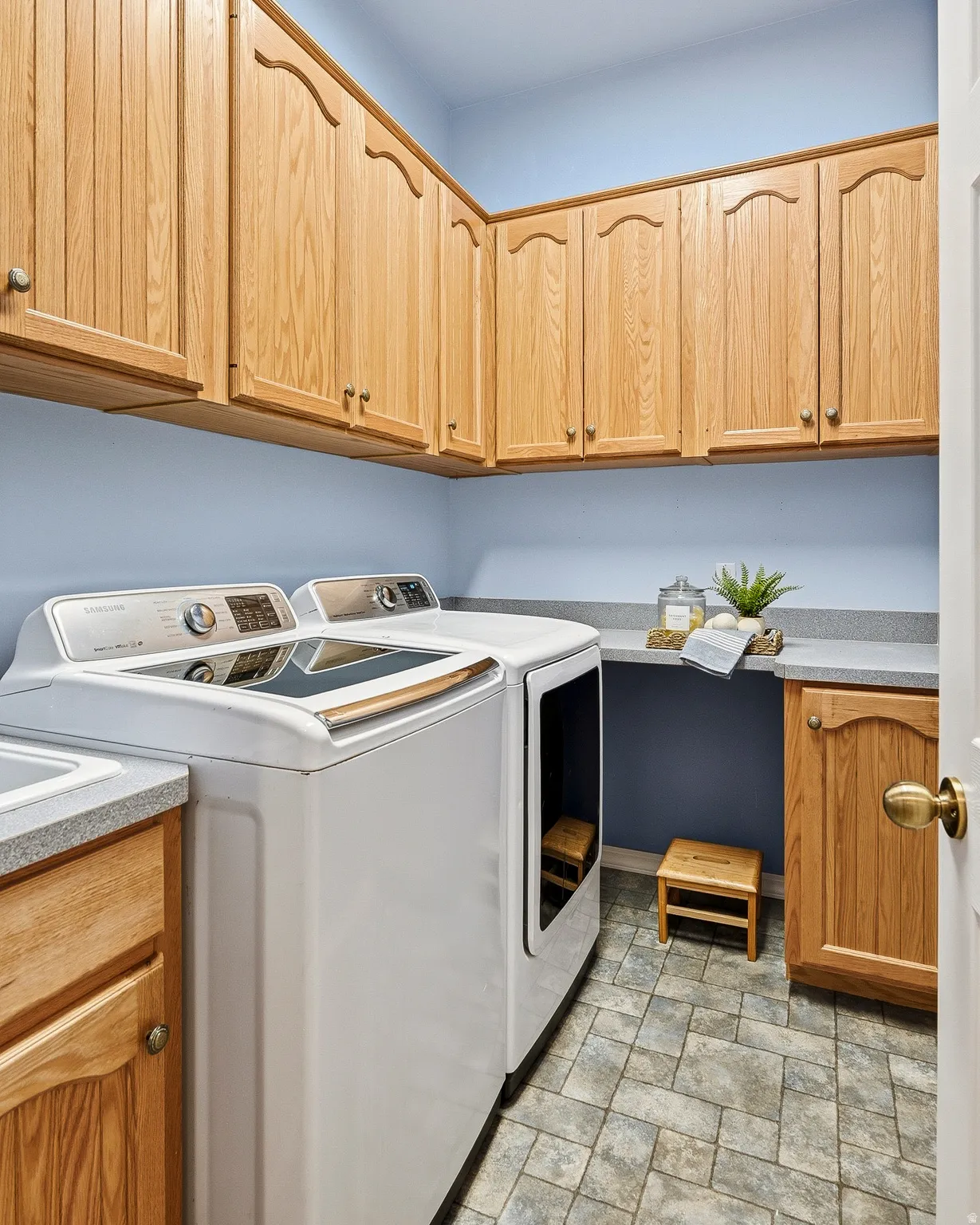 Laundry area featuring extensive wood cabinetry, light grey countertops, and tile-patterned flooring