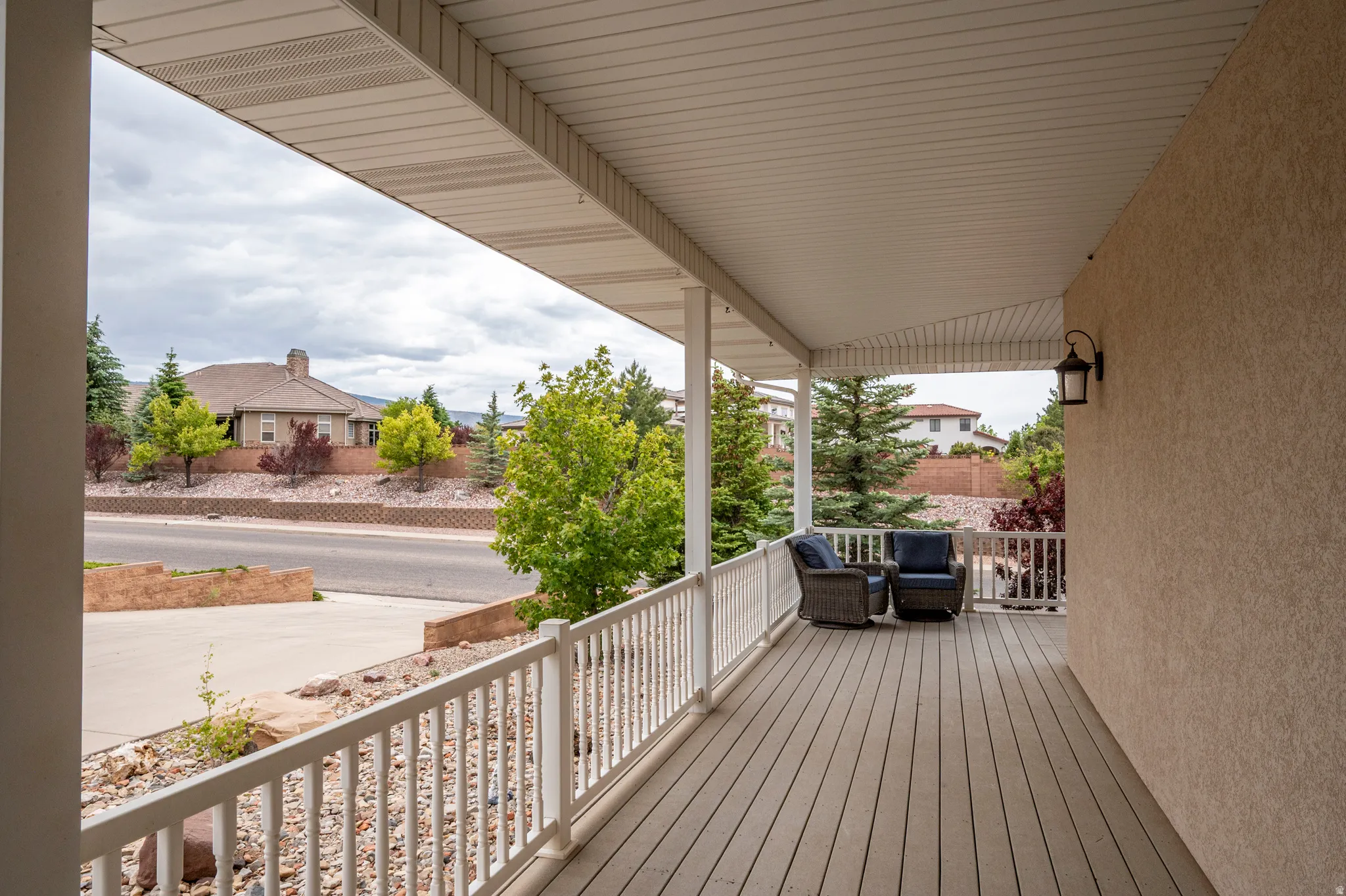 Covered porch featuring wood-finish flooring, white railing, and exterior wall sconce