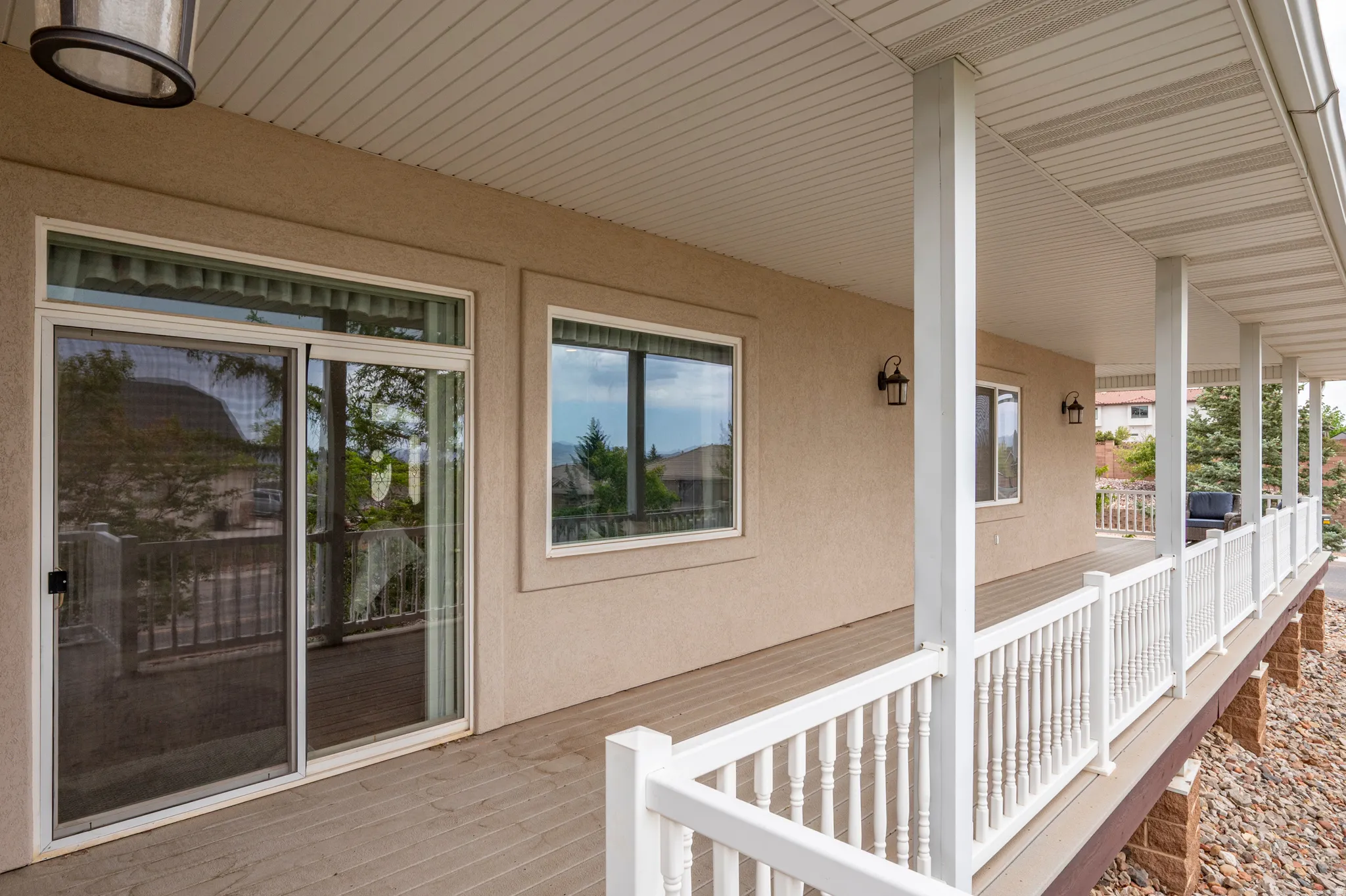 Spacious outdoor porch with textured decking, white balusters, and a stucco exterior