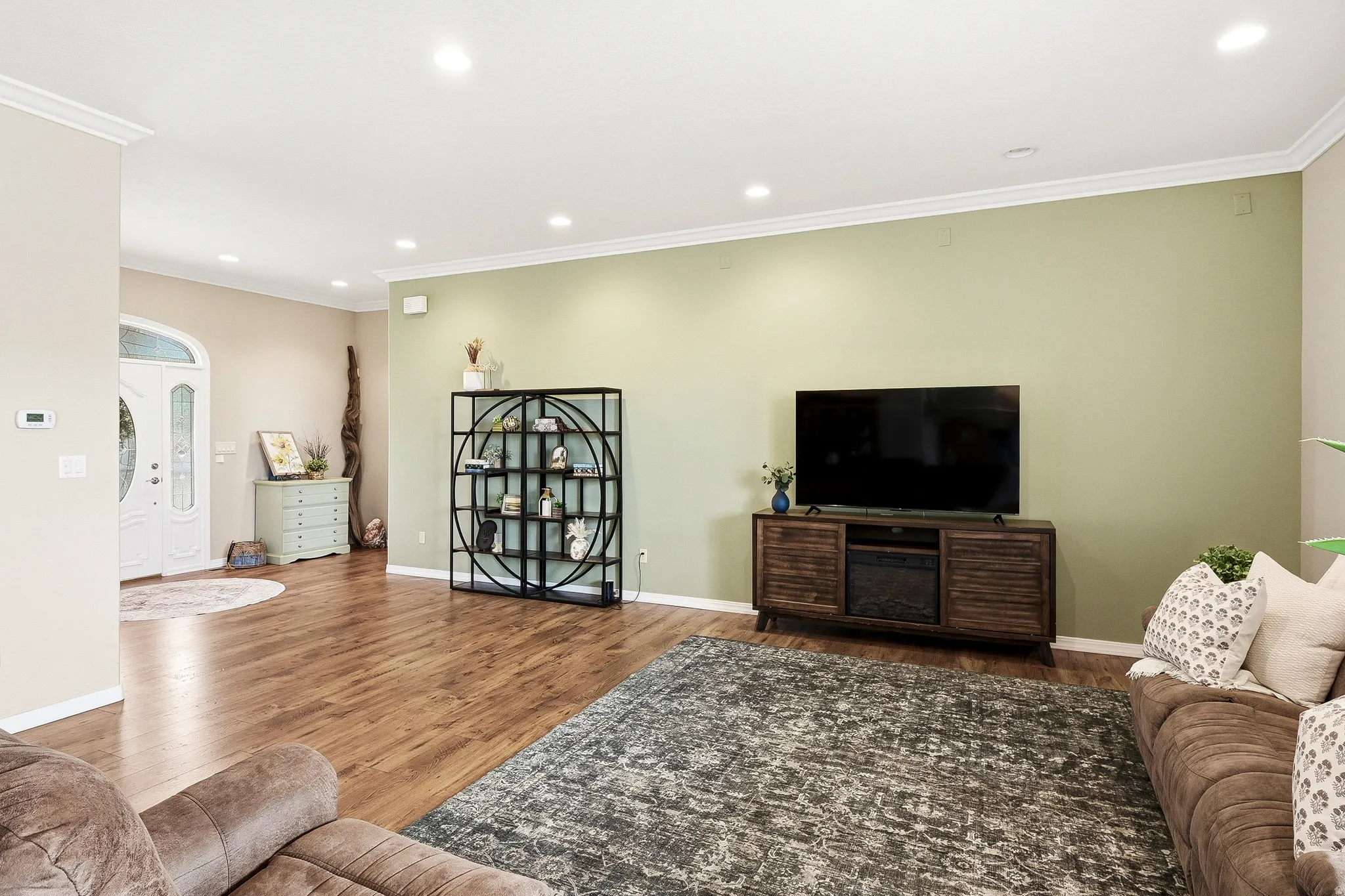 Expansive living area featuring wood-finish flooring, recessed lighting, and crown molding