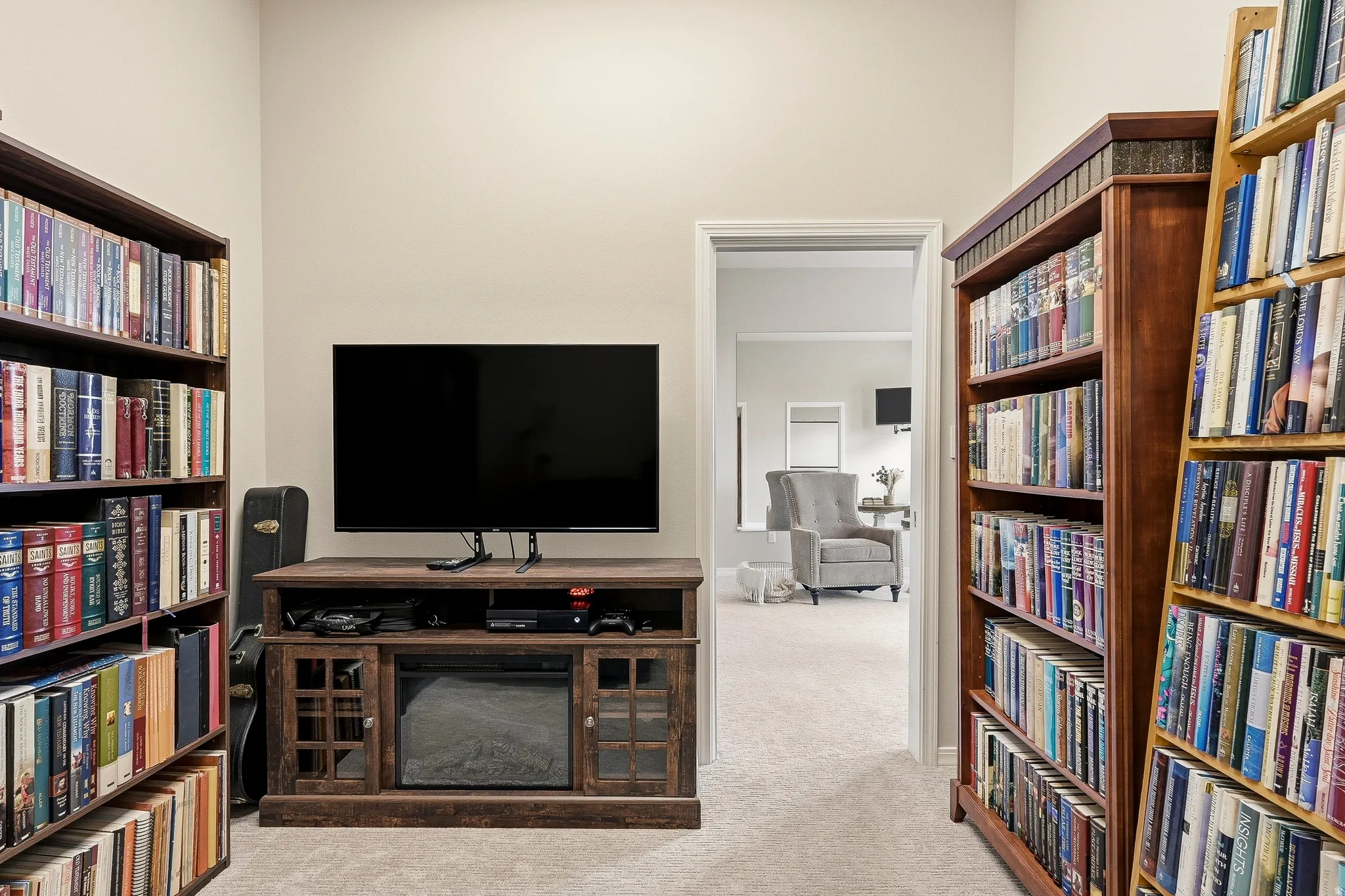 Built-in wood-finish shelving units frame a media console with an integrated electric fireplace, all set on plush carpet flooring