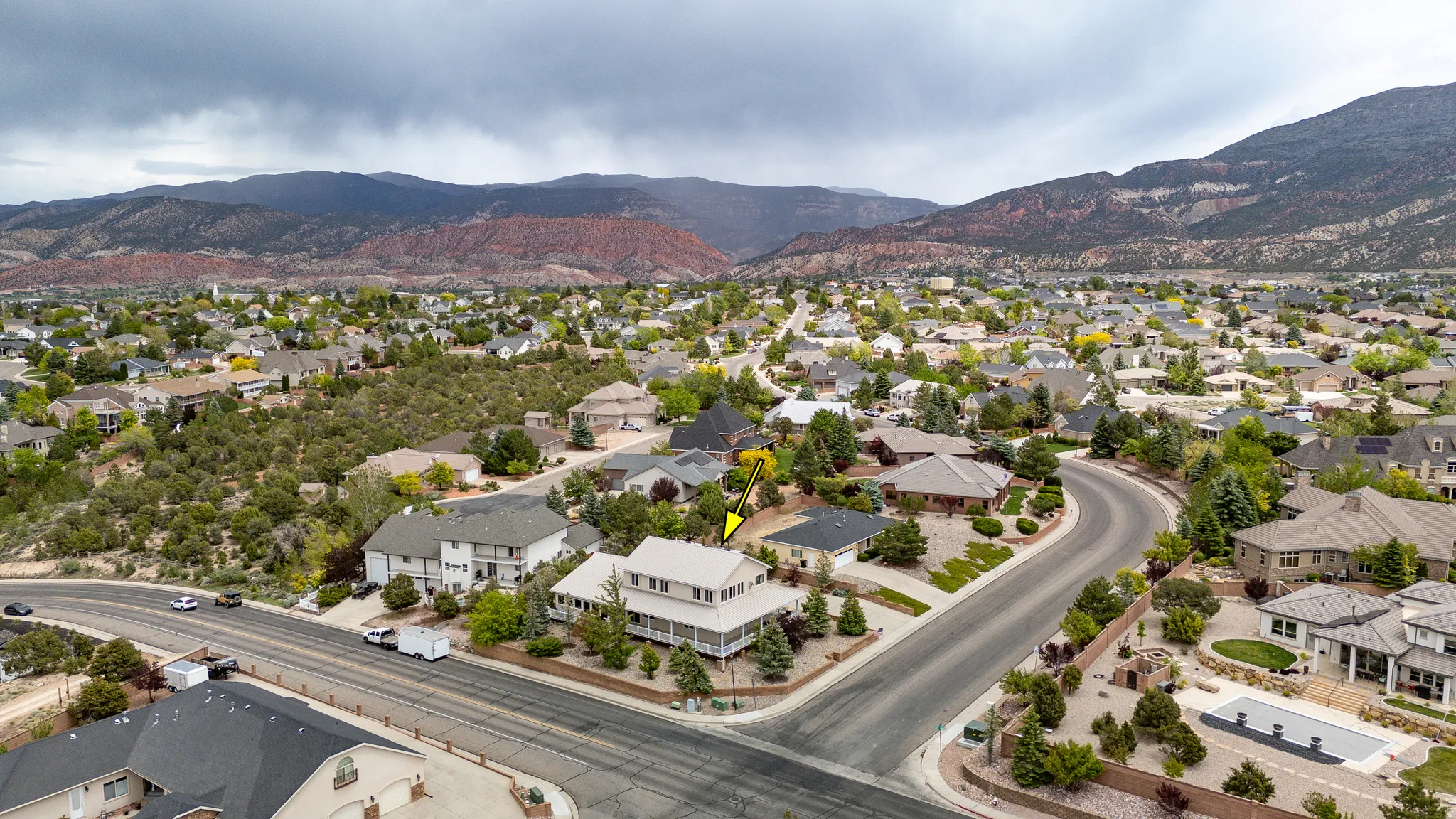 Residential neighborhood featuring a curved street, established trees, and mountain scenery