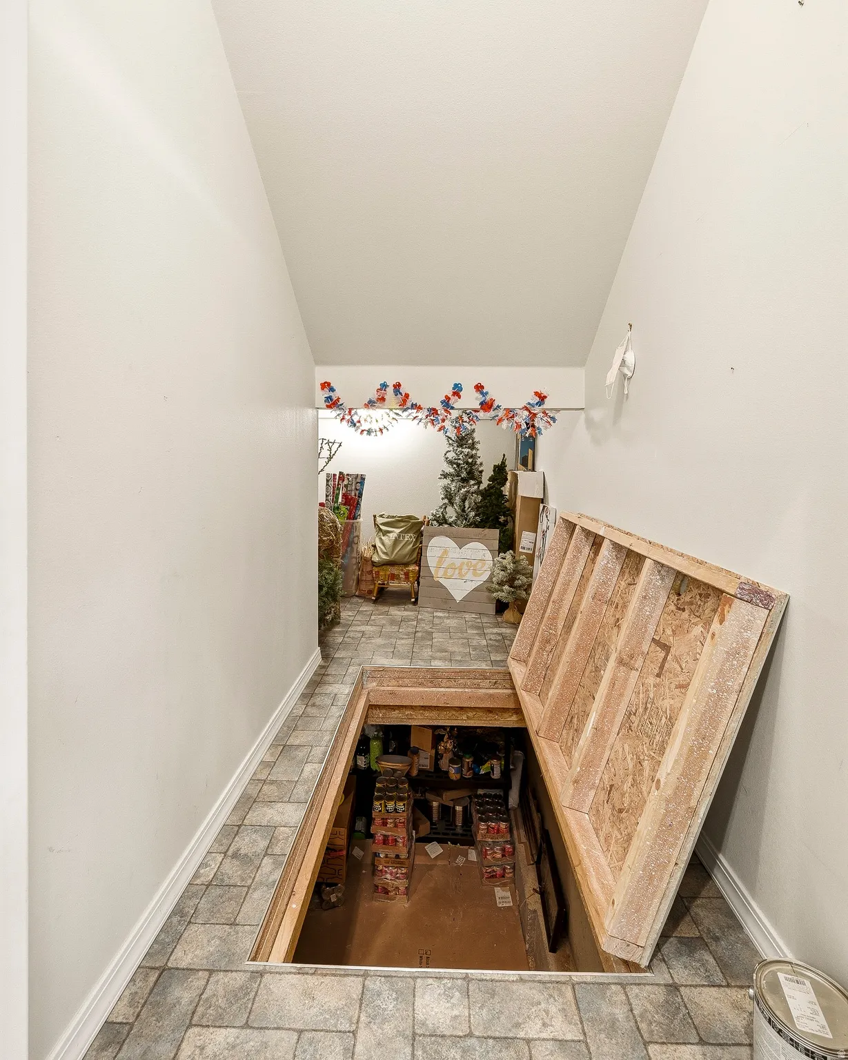 Interior hallway with gray-toned tile flooring, white baseboards, and a recessed floor access panel