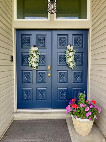 Double entry doors in a deep blue finish, featuring intricate carved panels and brass hardware