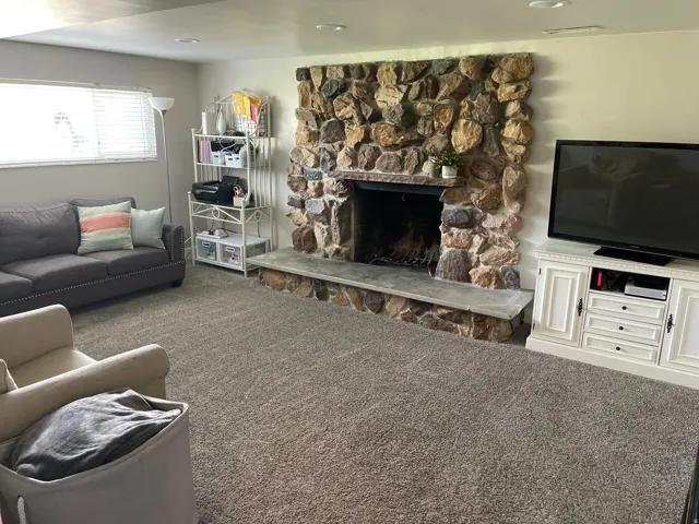 Stone-faced fireplace with a hearth, recessed lighting, and soft gray carpeting