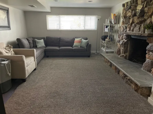 Spacious living area featuring a prominent stone fireplace with a stone hearth, carpeted flooring, and recessed lighting