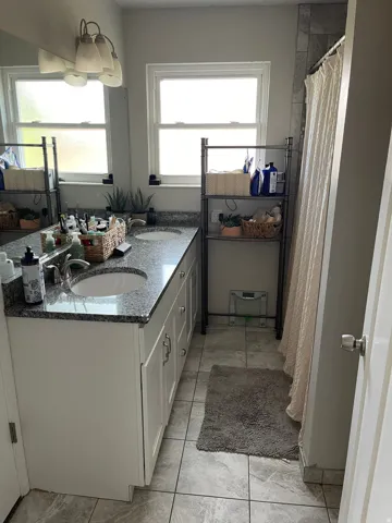 Double vanity with white cabinetry and granite countertops, featuring two undermount sinks and brushed nickel faucets