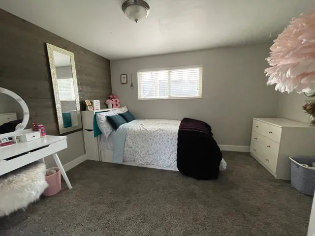 Bedroom featuring a wood-finish accent wall, light gray painted walls, and gray carpet