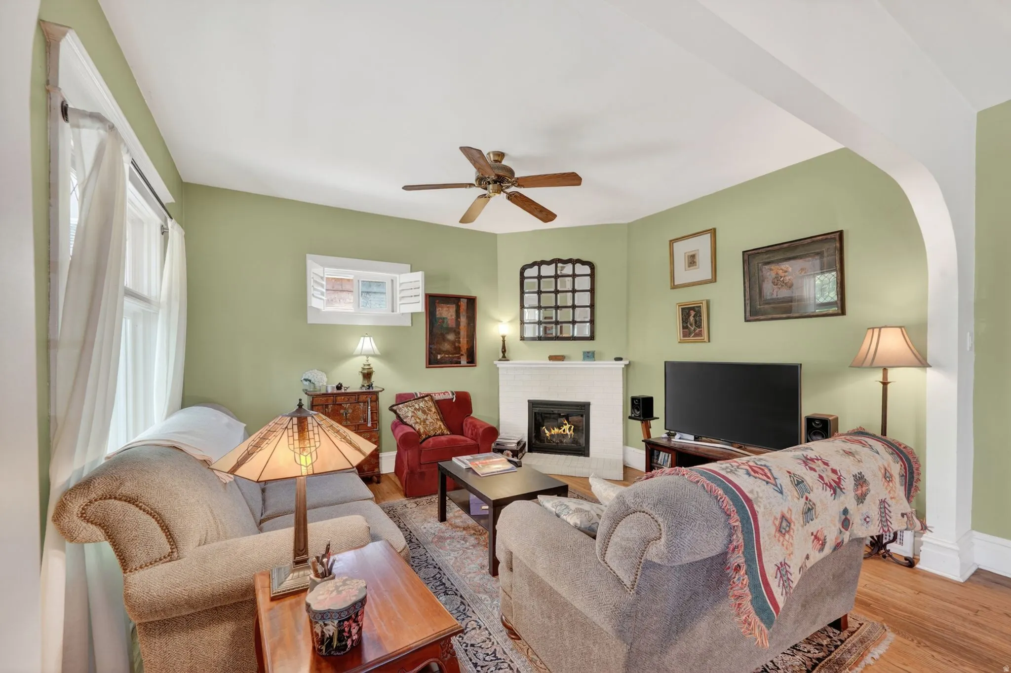 Living space featuring wood-finish flooring, an arched entryway, and a built-in fireplace with a white mantel