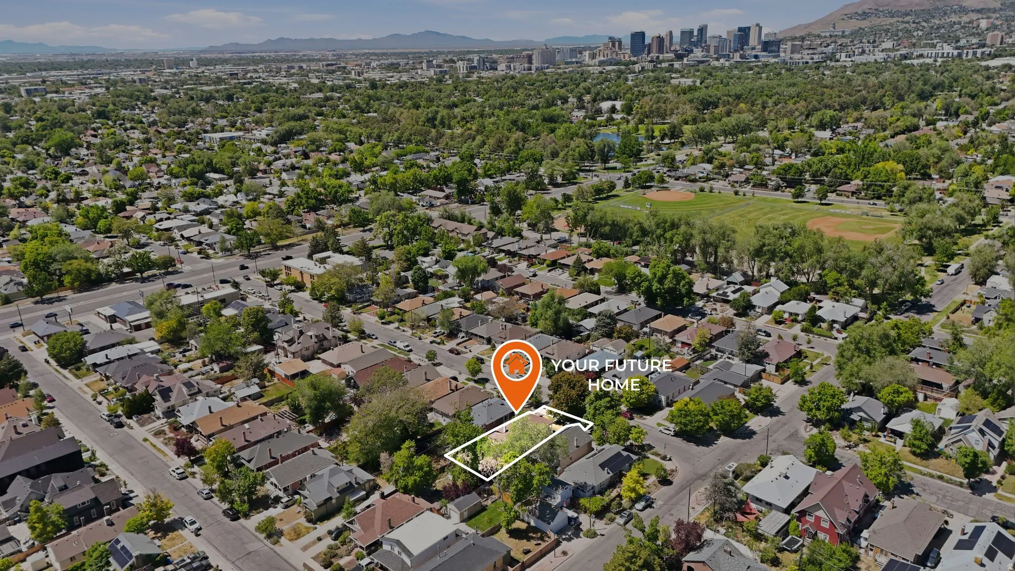 Aerial perspective of a residential neighborhood with a distant cityscape and mountainous backdrop