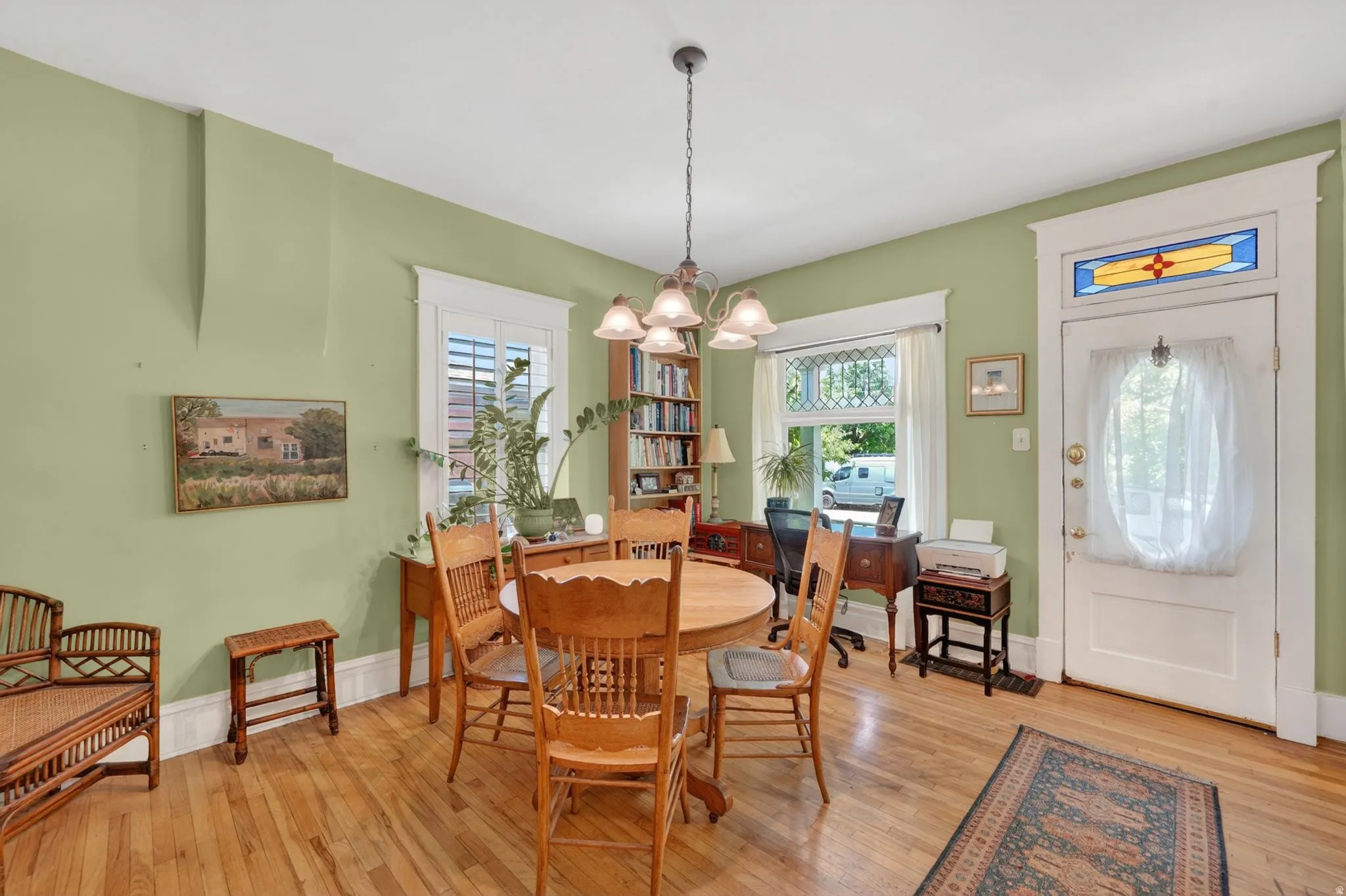 Hardwood flooring extends throughout this room, featuring a white paneled entry door with stained glass transom