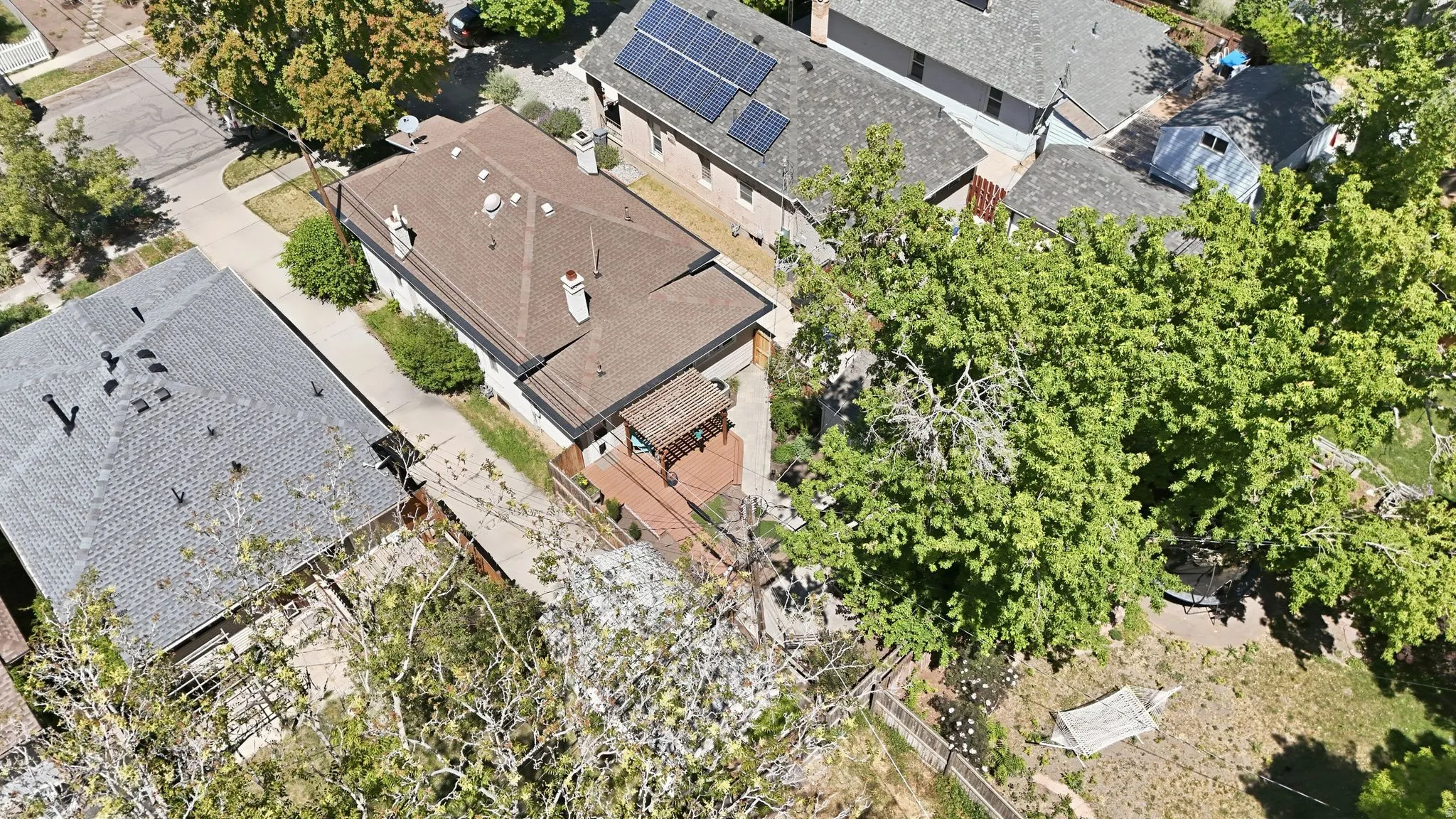 Aerial view showcasing a residential property with a brown shingle roof and multiple chimneys