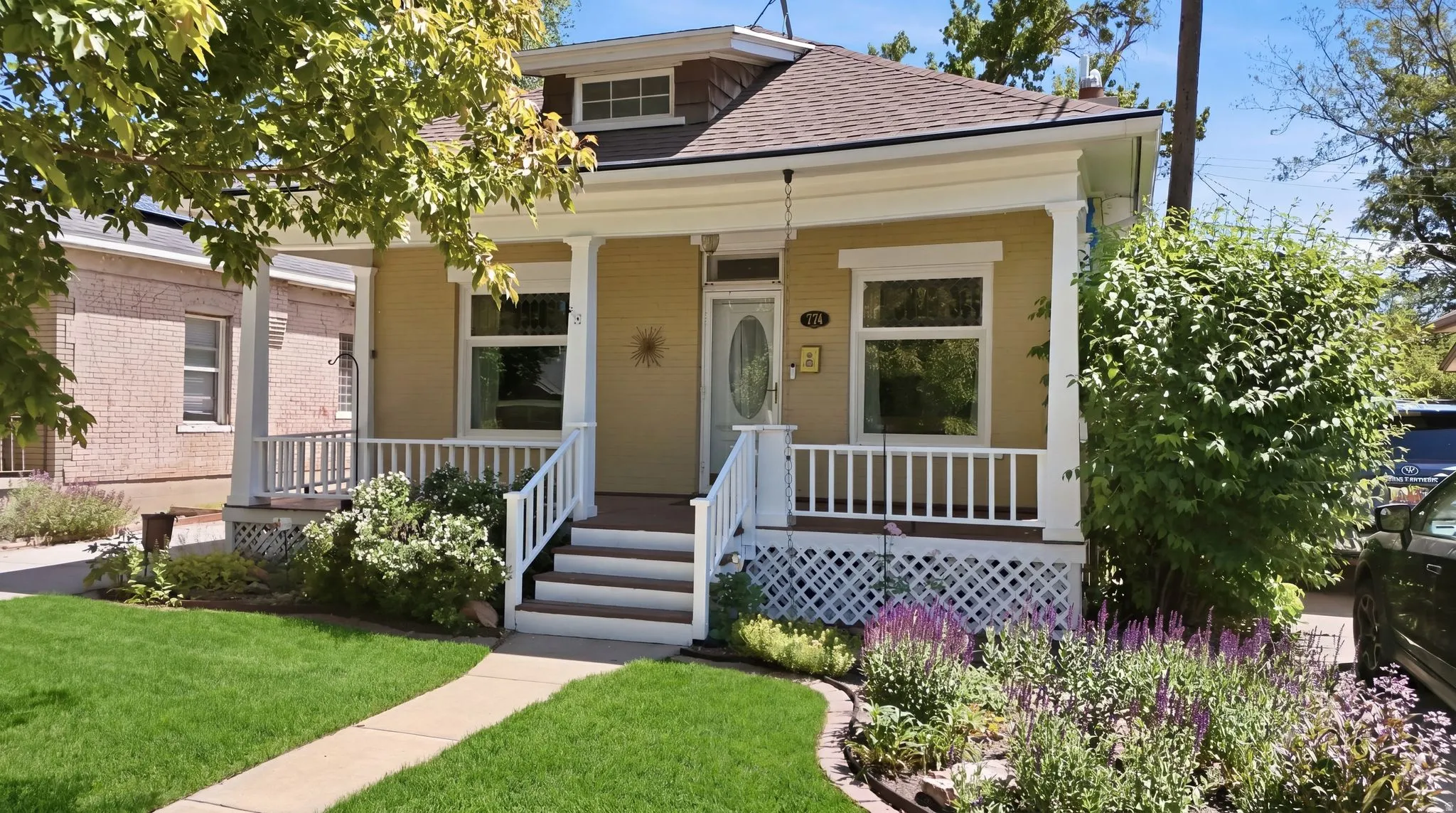 Inviting bungalow with a covered front porch featuring white columns and railing
