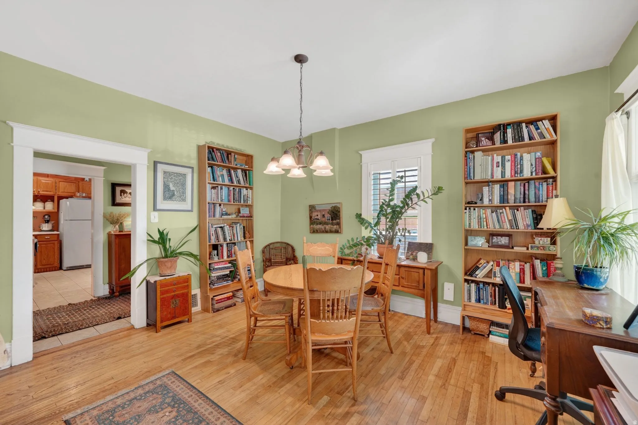 Hardwood flooring throughout a room featuring a chandelier and two built-in shelving units