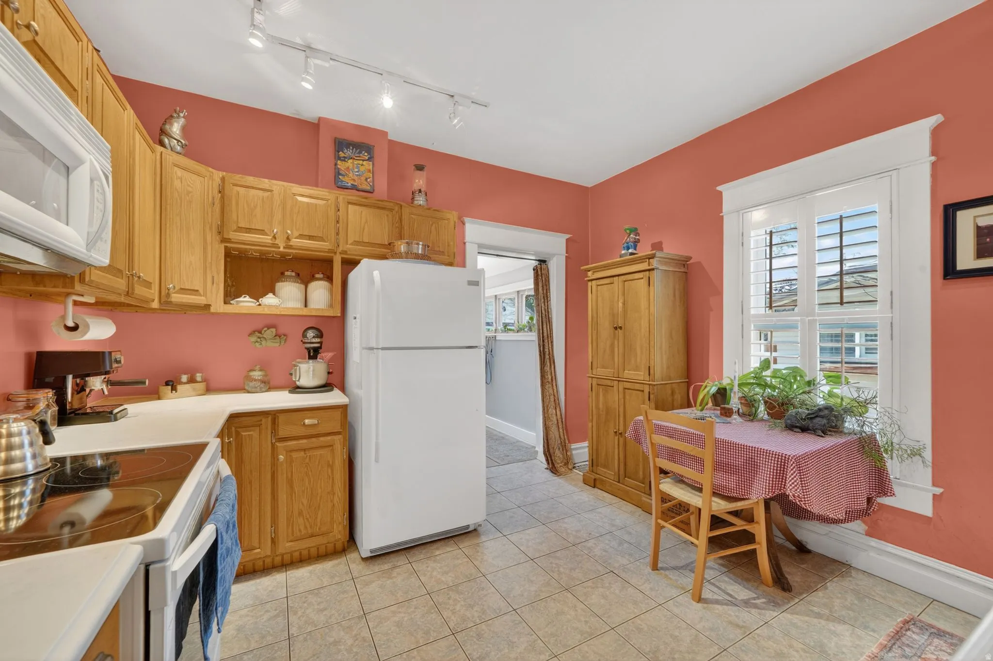 Kitchen featuring abundant wood cabinetry, white countertops, built-in range, track lighting, and a window with plantation shutters